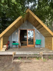a cabin with two green chairs on a wooden deck at The Tin Tent in King's Lynn