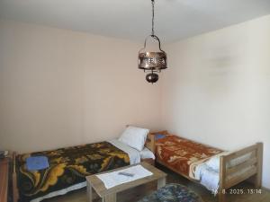 a room with two beds and a table and a chandelier at Apartman Jacević - Ljubenov in Donji Milanovac