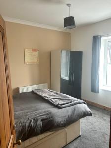 a bedroom with a bed and a black refrigerator at The Greenfield Inn Guest House in Llanelli