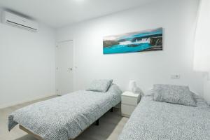 Un dormitorio con dos camas y un cuadro en la pared. en Apartamento New Metro 6pax, en Rivas-Vaciamadrid