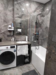a bathroom with a shower and a sink and a washing machine at Intourist Residence in Batumi