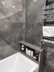 a bathroom with a white tub and a marble wall at Intourist Residence in Batumi