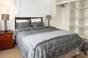 a bedroom with a bed with a gray comforter and two lamps at 2-Bed Cottage in Mount Pleasant, Harare in Harare