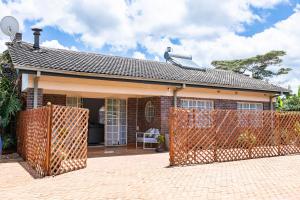 a brick house with a fence in front of it at 2-Bed Cottage in Mount Pleasant, Harare in Harare