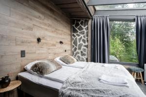 a bedroom with a bed with a wooden wall at Koskisviitti 3 - Private Lakeside Suite with Terrace in Laukaa +9 photos