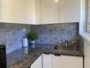 a kitchen with white cabinets and a sink at Cozy Stylish Granny Flat with Beautiful Garden View at MC 2079 in Mount Colah +12 photos