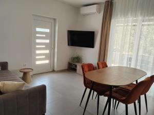 un soggiorno con tavolo, sedie e TV di Apartman Romanca a Vela Luka (Vallegrande)