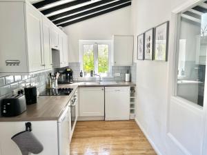 a kitchen with white cabinets and a wooden floor at Finest Retreats - Porth Cottage in Newquay