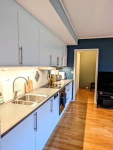 a kitchen with white cabinets and a wooden floor at Koselig og moderne 2-roms leilighet in Tromsø +1 photo