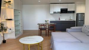 Una sala de estar con un sofá blanco y una cocina. en Modern 59m Sukhumvit 1BR - 31st Floor Pool - Gym, en Makkasan