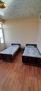 two beds in a room with a wooden floor at Avan Guesthouse 3 in Yerevan