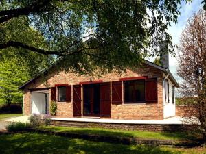 a brick house with red windows and a tree at Pet Escape in Ardennes in Baillamont