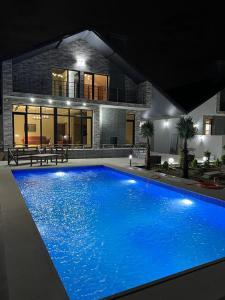 a large blue swimming pool in front of a house at VM Villa in Baku