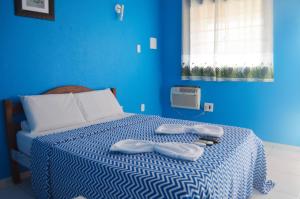um quarto azul com uma cama com duas toalhas em Pousada La Puerta Del Sol em Porto de Galinhas