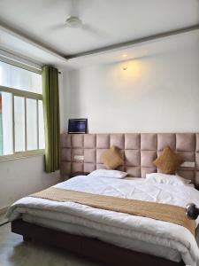a bedroom with a large bed with a brown headboard at Hotel Yoga Stay Rishikesh in Rishīkesh