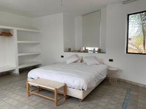 a white bedroom with a white bed and a stool at Villa blanche in Mirleft +33 photos