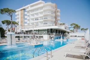 a hotel swimming pool with white chairs and a building at Hotel Carlton in Lido di Jesolo