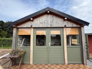 a small shed with green doors on a patio at 't Hoevehuisje in Beverwijk