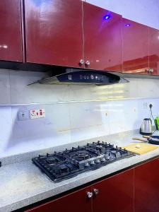 a stove top in a kitchen with red cabinets at Kstephen Apartment in Lekki +11 photos
