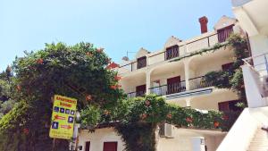 a building with a tree with red flowers on it at Apartments Maria in Cavtat
