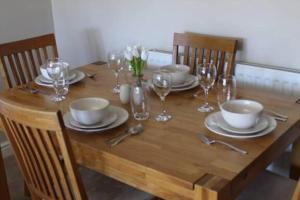 a wooden table with plates and wine glasses on it at 2 Bed House - Sleeps 4 - Pets - Garden - Parking in Elkesley +4 photos