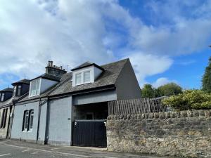 a white house with a stone wall at Foundry Street Apartment 3 - Dunfermline City Centre in Dunfermline
