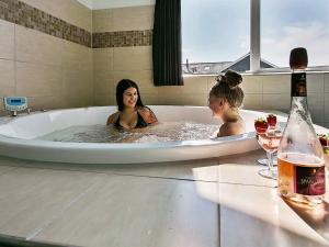 two women in a bath tub with a bottle of wine at Luxury Pool Retreat by Sea - By Traum Ferienwohnungen in Bogense