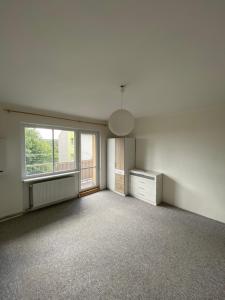 Una sala de estar vacía con una ventana y una cómoda. en Tisá byt, en Ústí nad Labem