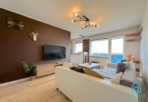 Una sala de estar con un sofá blanco y un televisor. en Postcard Apartment Scenic Escape 10 Minutes to Gdańsk Old Town and Seaside, en Gdansk