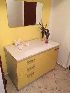 a bathroom with a yellow vanity with a mirror at Apartments Wagner in Dobrinj