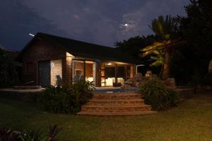 Una casa de ladrillo con escaleras que conducen a ella por la noche. en whales tail, en Port Shepstone