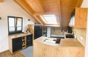 a kitchen with black appliances and a wooden ceiling at FeWo Leni - Modernes Apartment mit Bergblick - Zentral gelegen in Mittenwald