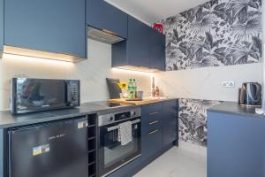 a kitchen with blue cabinets and a microwave and a stove at Trinity- New Modern Apartment with FREE on road parking in Cambridge