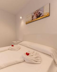a bedroom with two white beds with red roses on them at Apartamento acogedor con Piscina en Tenerife in Icor