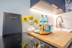 a kitchen counter with bottles of water and a vase with flowers at Trinity- New Modern Apartment with FREE on road parking in Cambridge +36 photos