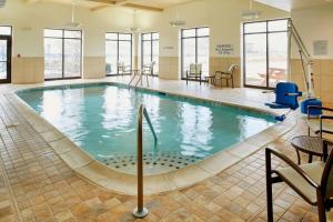 a pool in a hotel with chairs and tables at Courtyard Hamilton in Hamilton