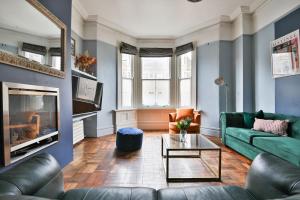 a living room with a green couch and a fireplace at Elegant Victorian Home with Pool Table & Parking in Cardiff