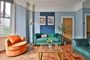a living room with two green couches and a table at Elegant Victorian Home with Pool Table & Parking in Cardiff