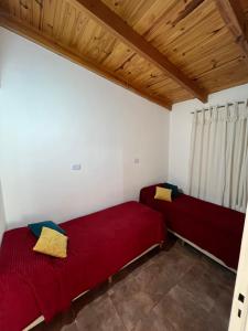 two beds in a room with white walls and wooden ceilings at Cabaña brisas del lago in Villa Parque Siquiman