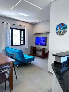 a living room with a blue couch and a tv at Apto Funcional próximo a Orla do Centro HS4 in Ubatuba
