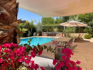ein Swimmingpool mit einem Tisch und einigen rosa Blumen in der Unterkunft Dar Muezza in Aghmat