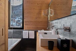 a bathroom with a sink and a bath tub at Unique Hotel Post in Zermatt