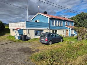 ein Auto, das vor einem blauen Haus parkt in der Unterkunft The Blue house apartment in Andøya
