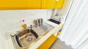 a sink in a small kitchen with yellow cabinets at PPL Studio Apartments in Sheffield
