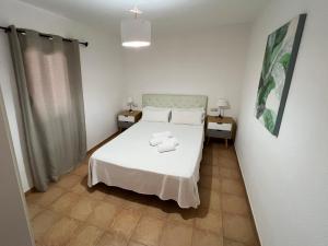 a bedroom with a white bed and two night stands at Anahi Home Corralejo - Villa Cardon 12 in La Oliva
