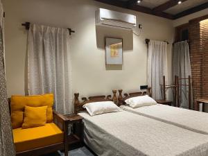 a bedroom with two beds and a fan and a chair at Rimil Homestay Santiniketan in Shānti Niketan