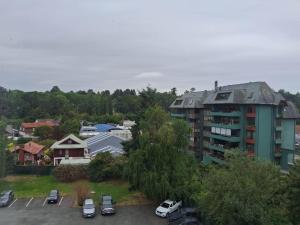 a parking lot with cars parked in front of a building at Departamento Los Carrera Centro in Osorno