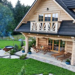 een houten huis met een terras en een open haard bij Leśny Zakątek Zawoja in Stryszawa