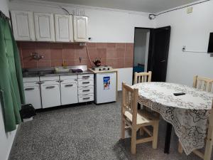 a kitchen with white cabinets and a table and a table and a table at Don Oscar Alojamientos Dpto Sol in San Justo