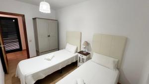 a bedroom with two beds and a night stand with a lamp at Anahi Homes Corralejo- Dracaena 18 in La Oliva +9 photos